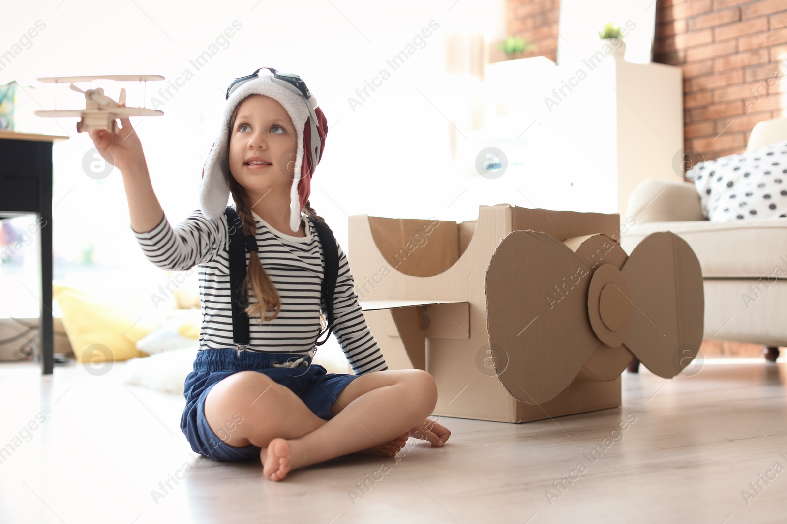Photo of Adorable little child playing with toy plane at home