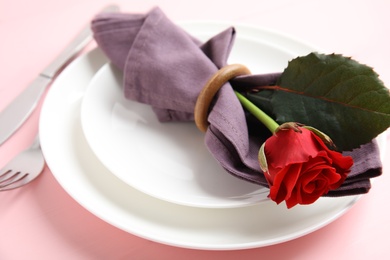 Photo of Beautiful table setting with red flower on pink background. Valentine's day romantic dinner