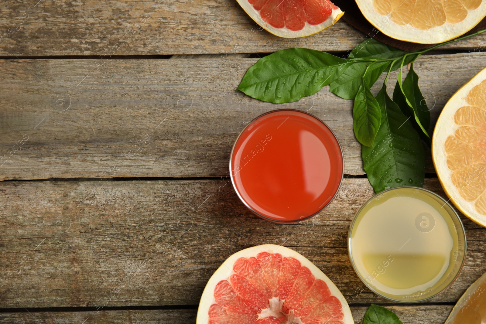 Photo of Glasses of different pomelo juices and fruits on wooden table, flat lay. Space for text