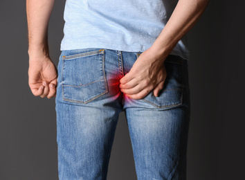 Image of Man suffering from hemorrhoid on black background, closeup