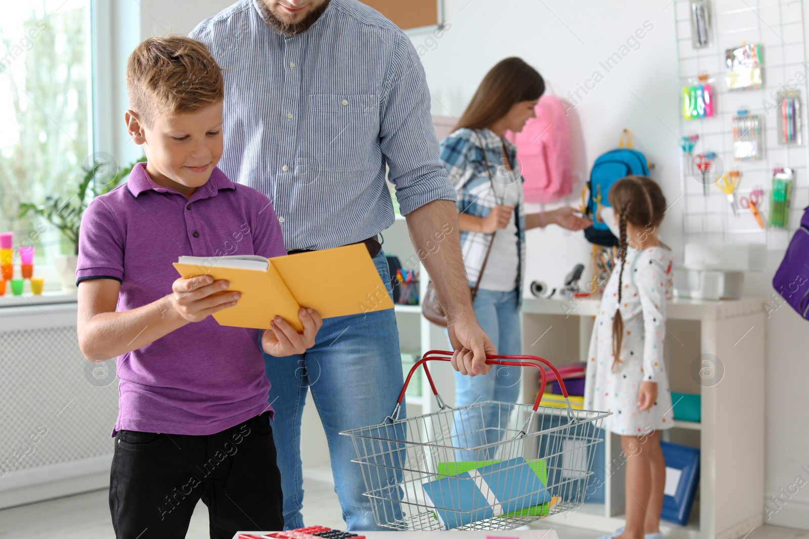 Photo of Little boy choosing school supplies with father in stationery shop