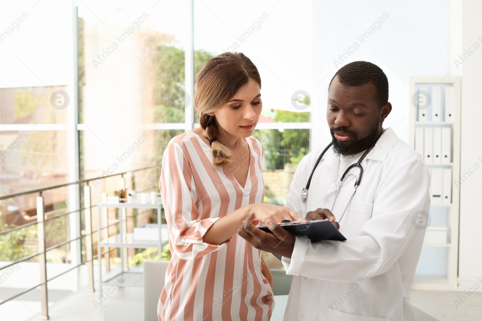 Photo of Young African-American doctor consulting patient in hospital