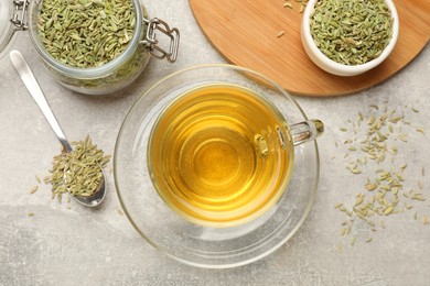 Photo of Aromatic fennel tea and seeds on light grey table, flat lay