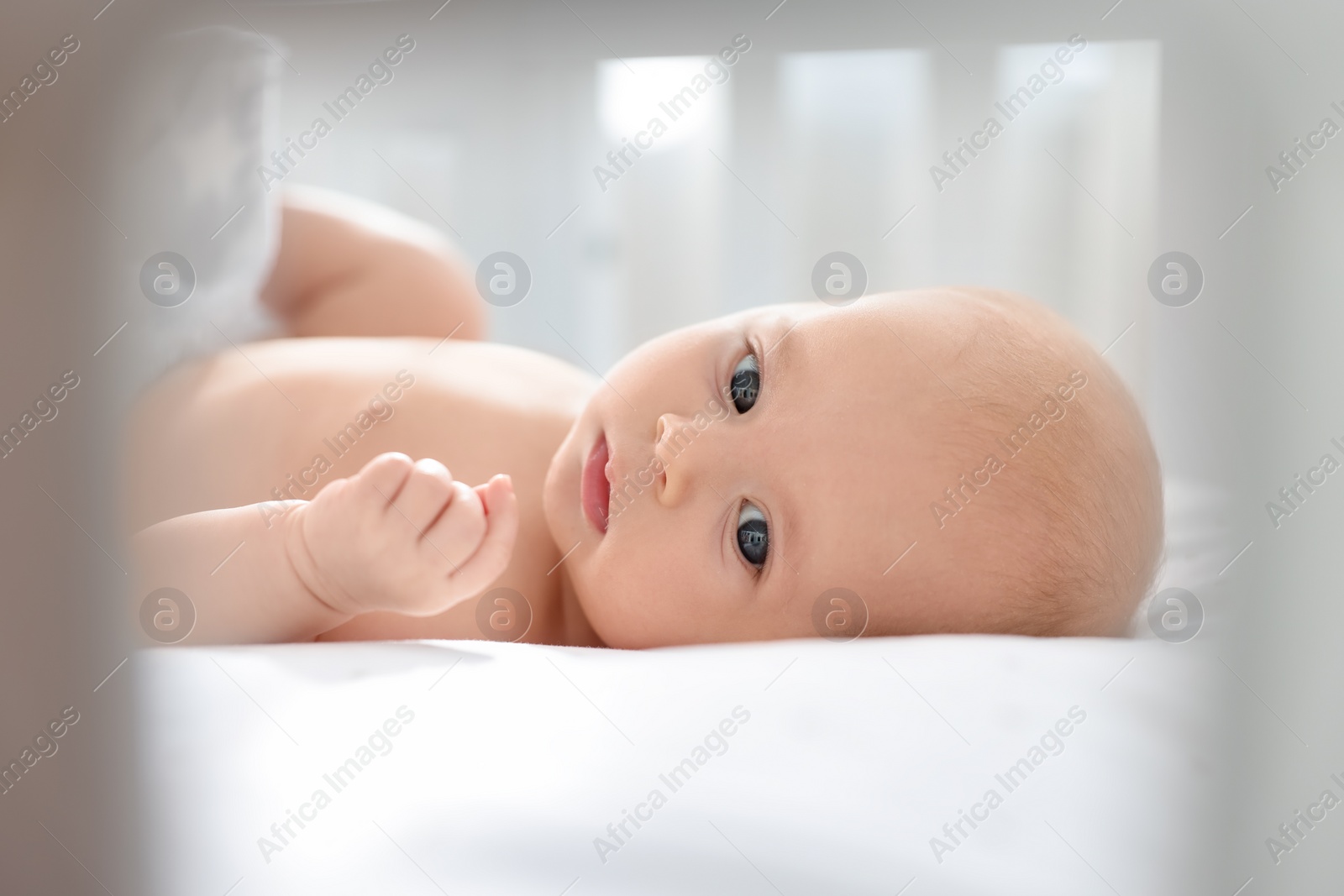 Photo of Cute little baby lying in crib at home