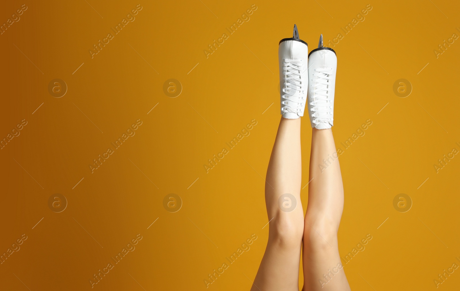 Photo of Woman in elegant white ice skates on yellow background, closeup of legs. Space for text