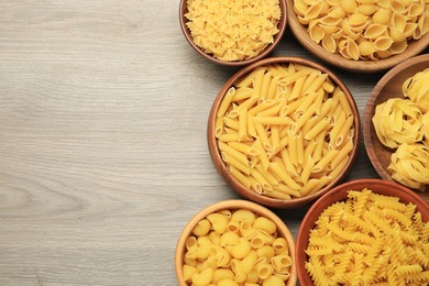 Photo of Different types of pasta on light grey wooden table, flat lay. Space for text