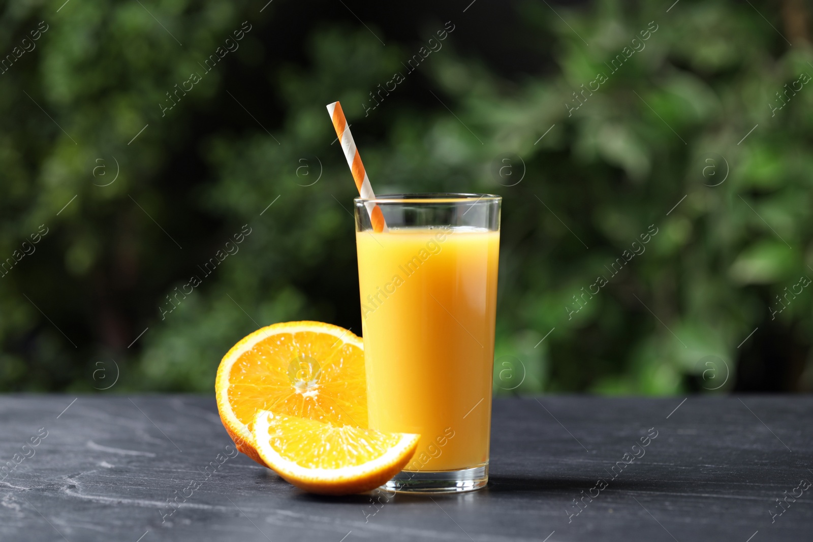 Photo of Glass of orange juice and fresh fruits on grey table