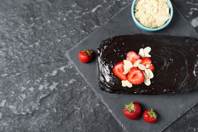 Photo of Delicious chocolate sponge cake with strawberry and almond flakes on black table, flat lay. Space for text