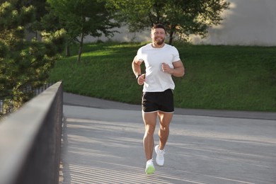 Smiling man running outdoors on sunny day
