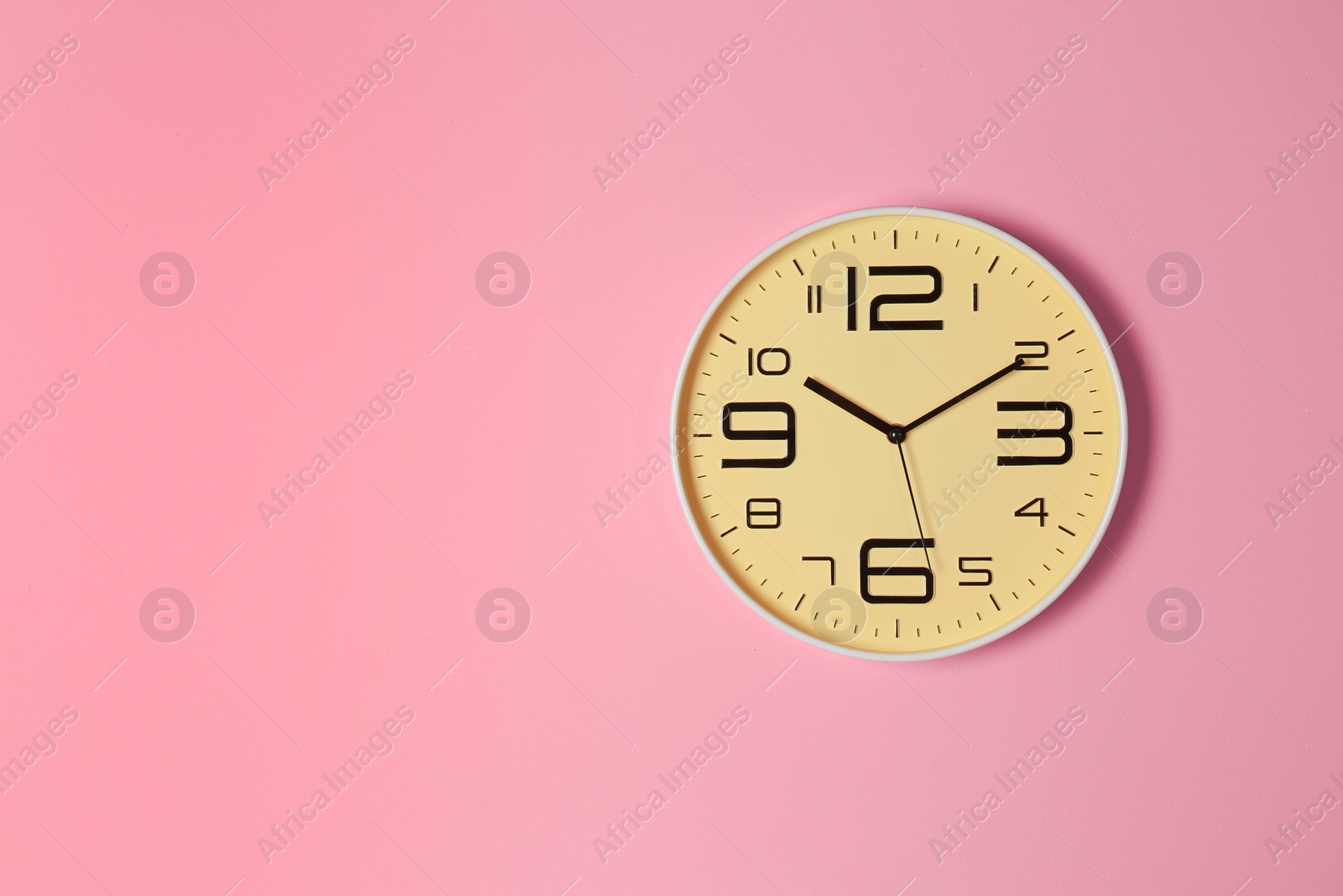 Photo of Stylish analog clock hanging on color wall. Space for text