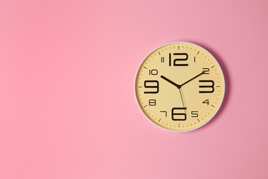Stylish analog clock hanging on color wall. Space for text