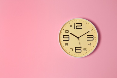 Photo of Stylish analog clock hanging on color wall. Space for text