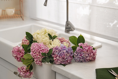 Photo of Bouquet with beautiful hydrangea flowers in sink