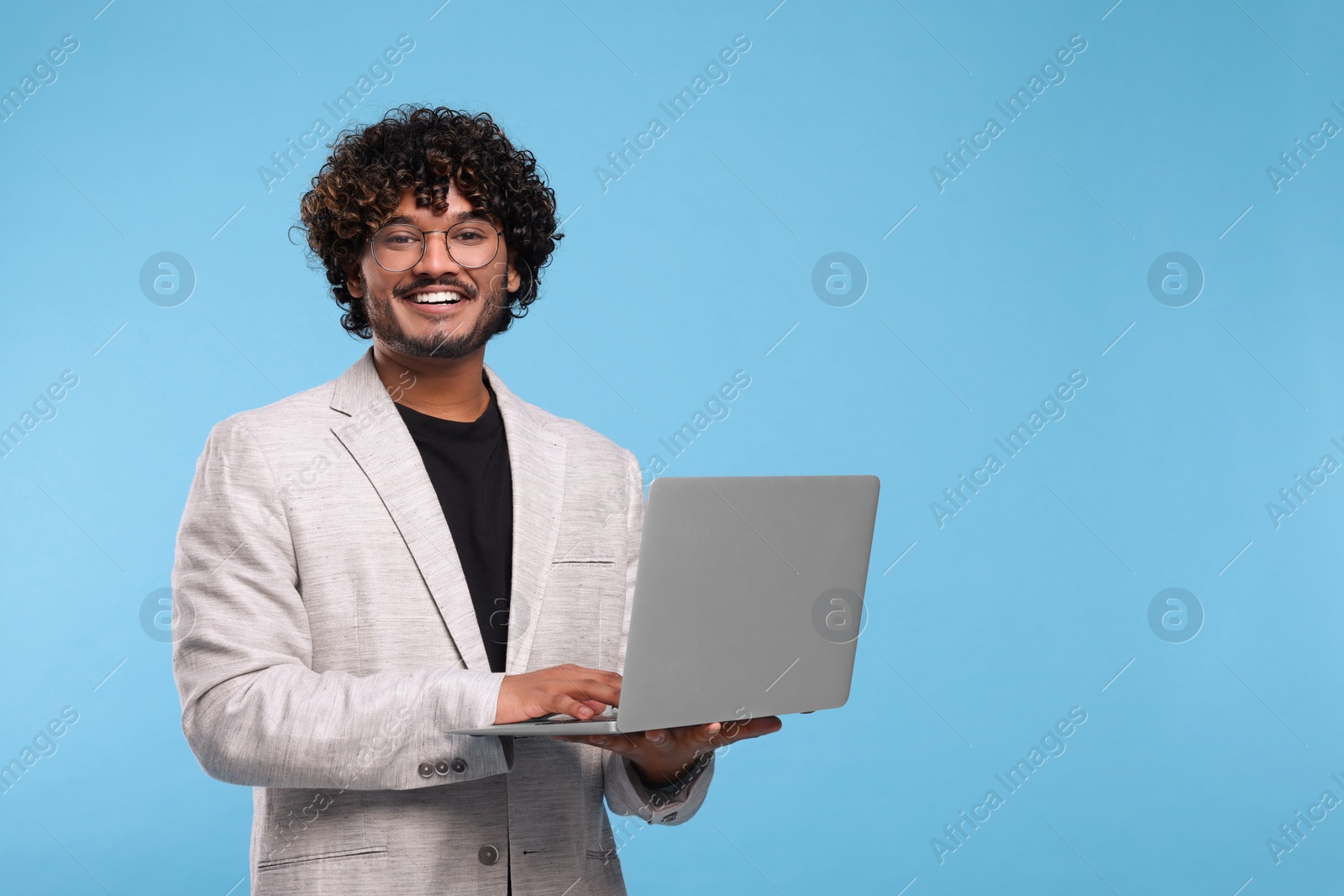 Photo of Smiling man with laptop on light blue background, space for text