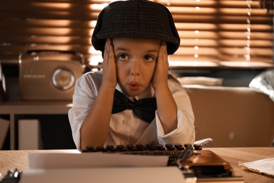 Photo of Cute little detective at table in office