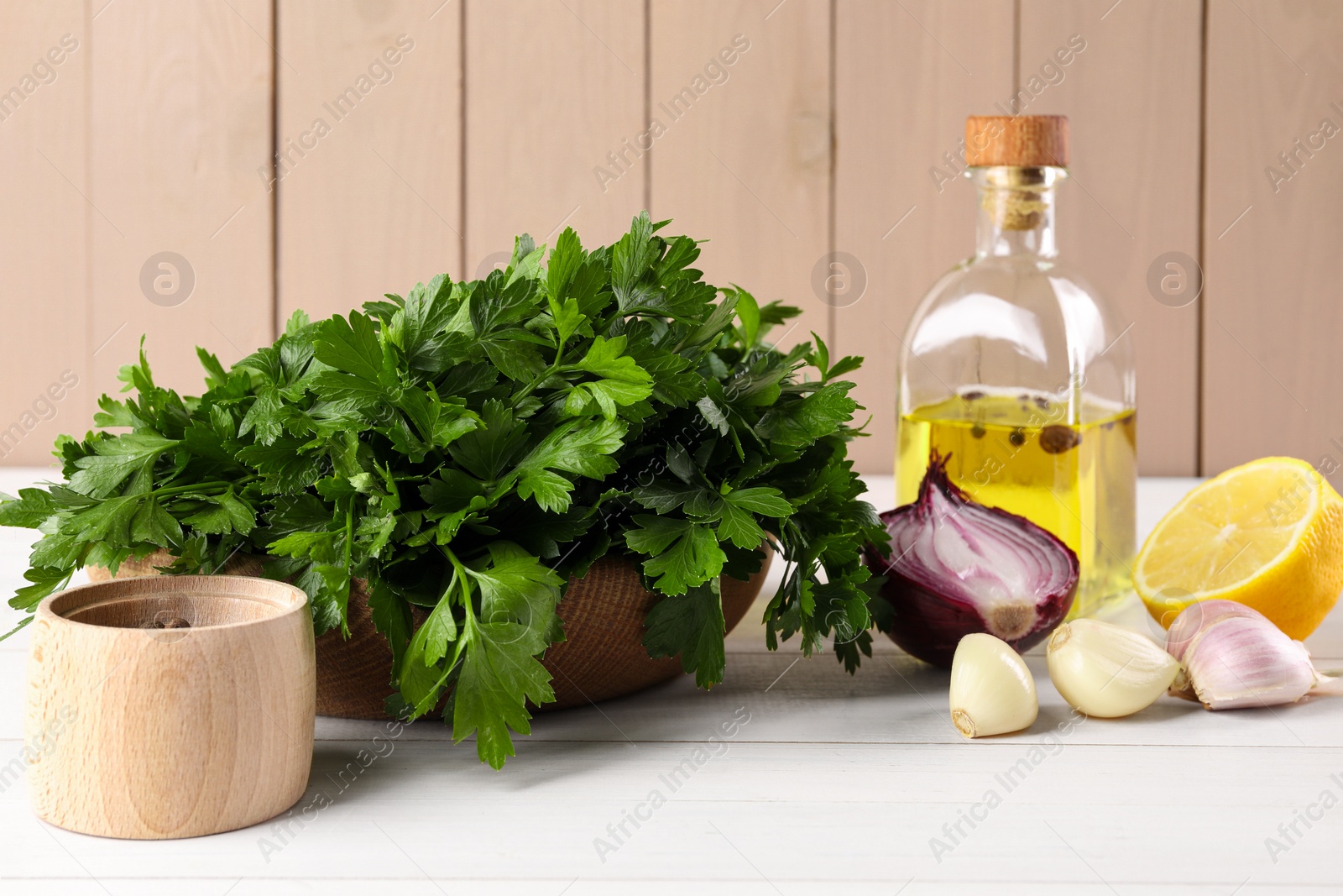 Photo of Fresh green parsley, spices and other products on white wooden table