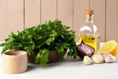 Photo of Fresh green parsley, spices and other products on white wooden table