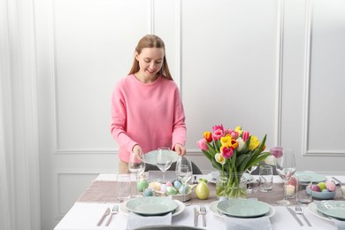 Photo of Woman setting table for festive Easter dinner at home