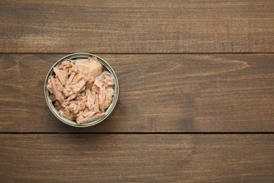 Tin can with canned tuna on wooden table, top view. Space for text