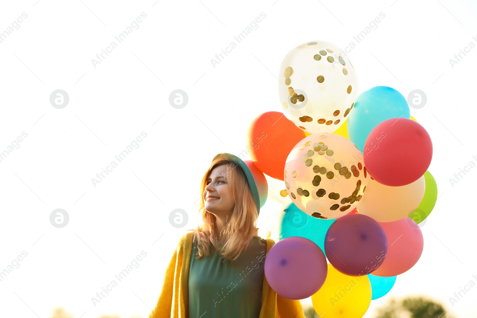 Photo of Young woman with colorful balloons outdoors on sunny day