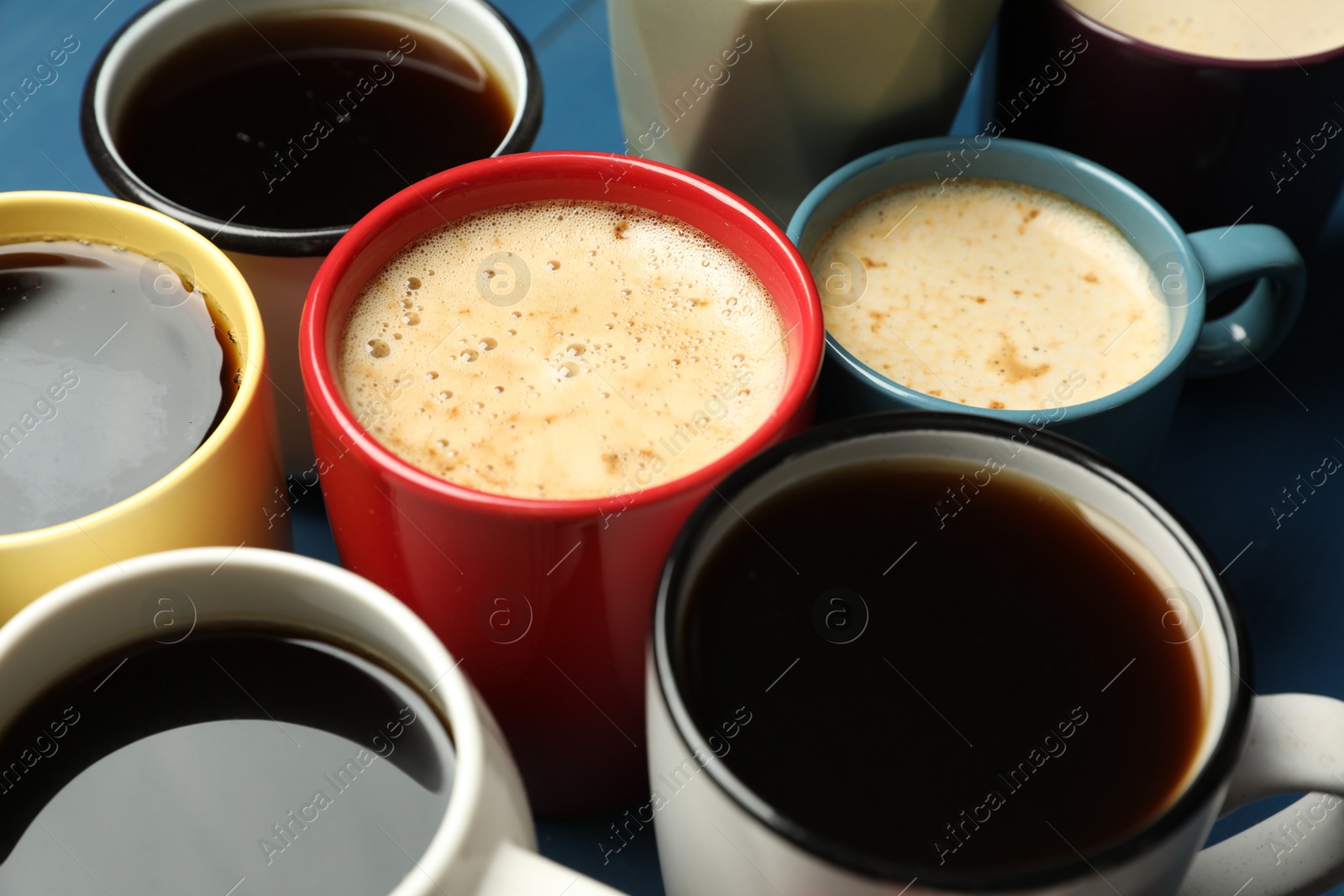 Photo of Many cups of different coffee drinks on blue table