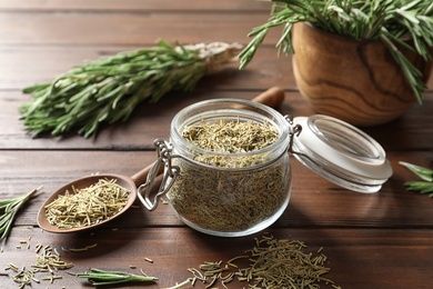 Photo of Jar with dried rosemary and twigs on wooden table