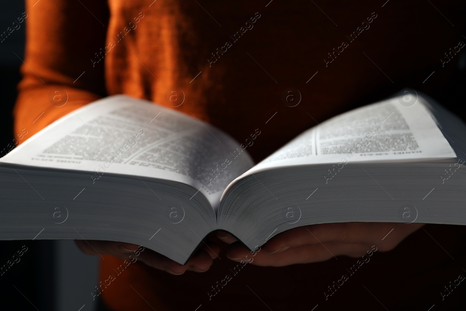 Photo of Woman reading Bible against black background, closeup