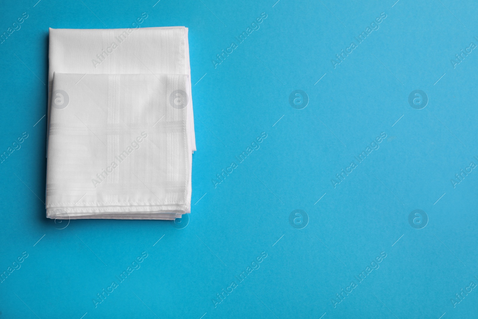 Photo of Stylish white handkerchiefs on light blue background, flat lay. Space for text