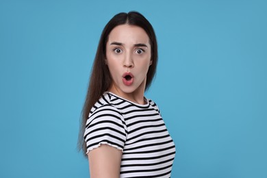 Portrait of surprised woman on light blue background