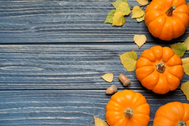 Flat lay composition with pumpkins and autumn leaves on blue wooden table. Space for text