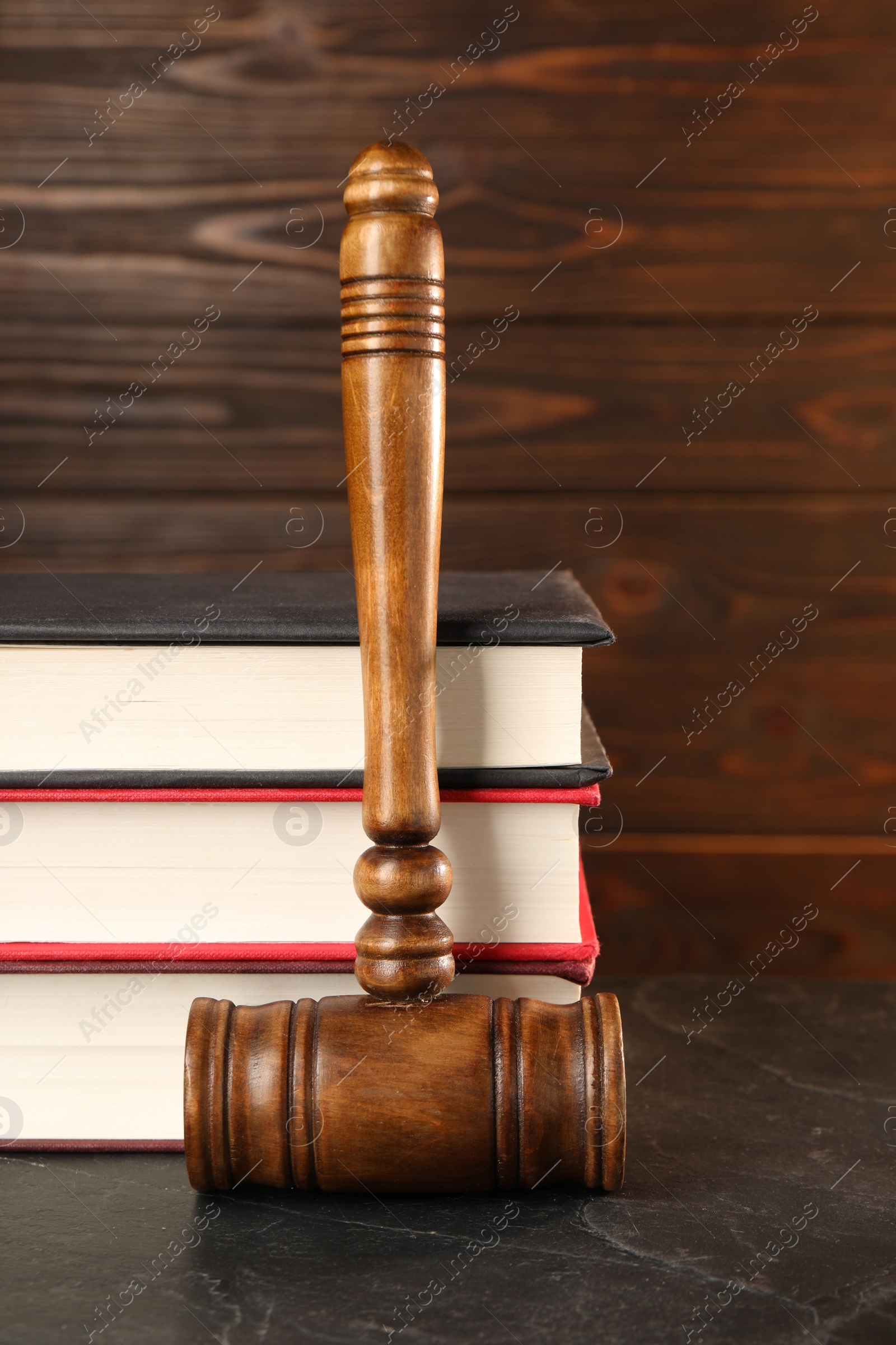 Photo of Wooden gavel and stack of books on dark textured table