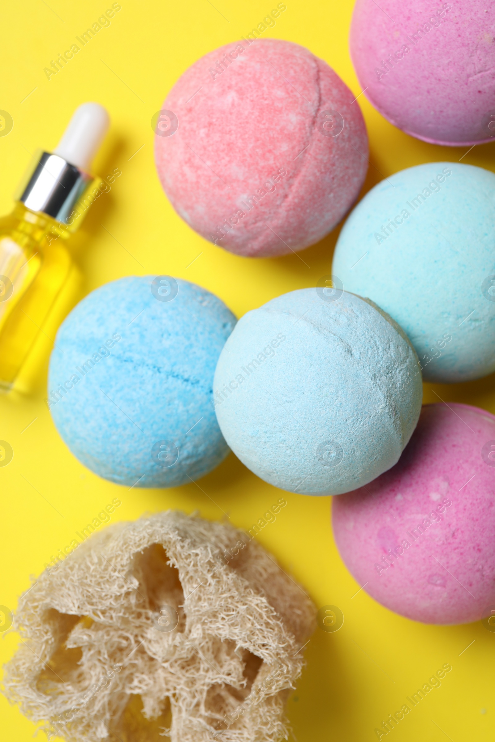 Photo of Bath bombs, loofah sponge and bottle on yellow background, above view