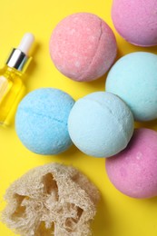 Bath bombs, loofah sponge and bottle on yellow background, above view