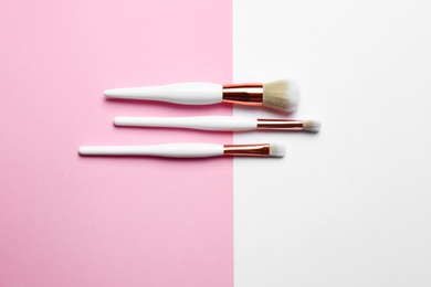 Different makeup brushes on color background, flat lay. Space for text