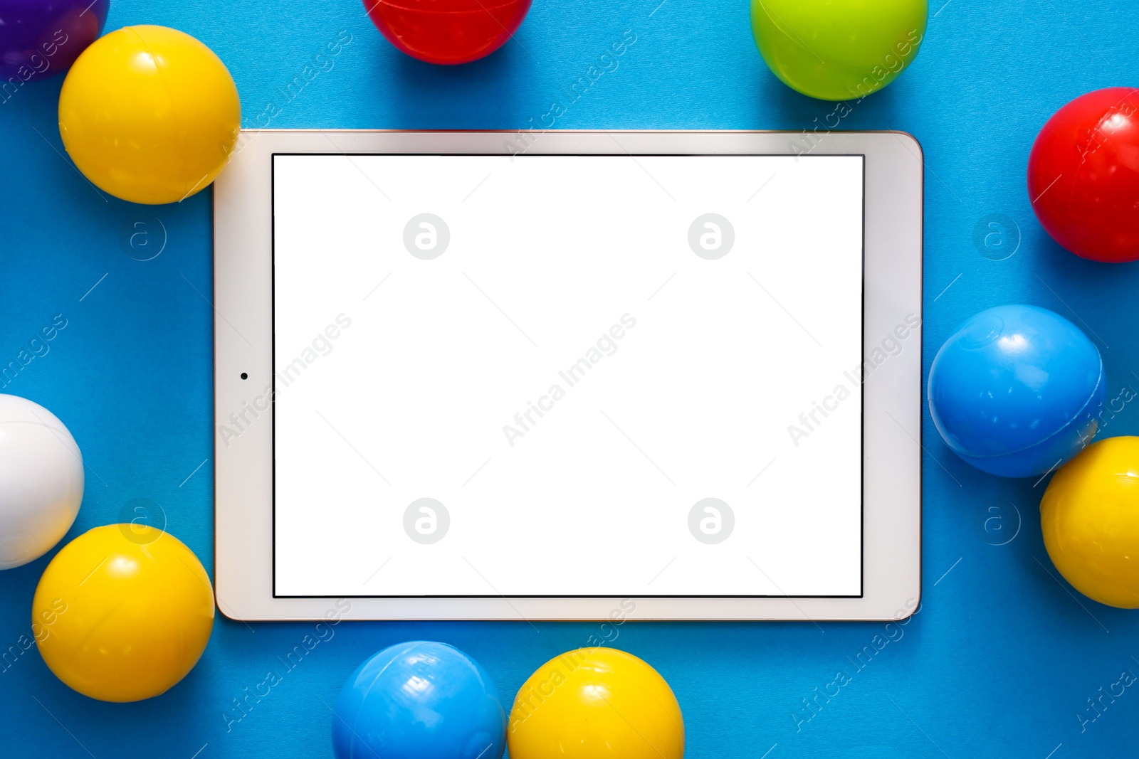 Photo of Modern tablet and balls on light blue background, flat lay. Space for text