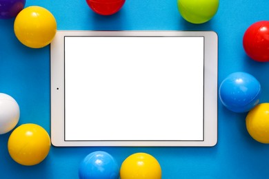 Modern tablet and balls on light blue background, flat lay. Space for text