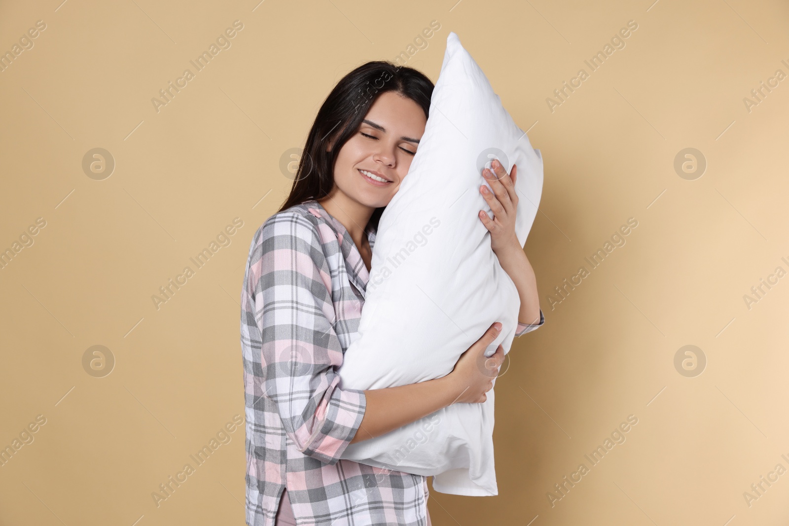 Photo of Sleepy young woman with soft pillow on beige background