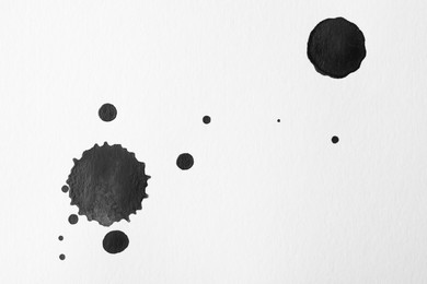 Blots of black ink on white background, flat lay