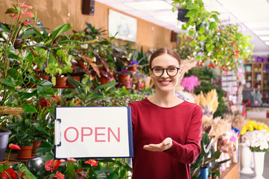 Photo of Female business owner holding OPEN sign in flower shop