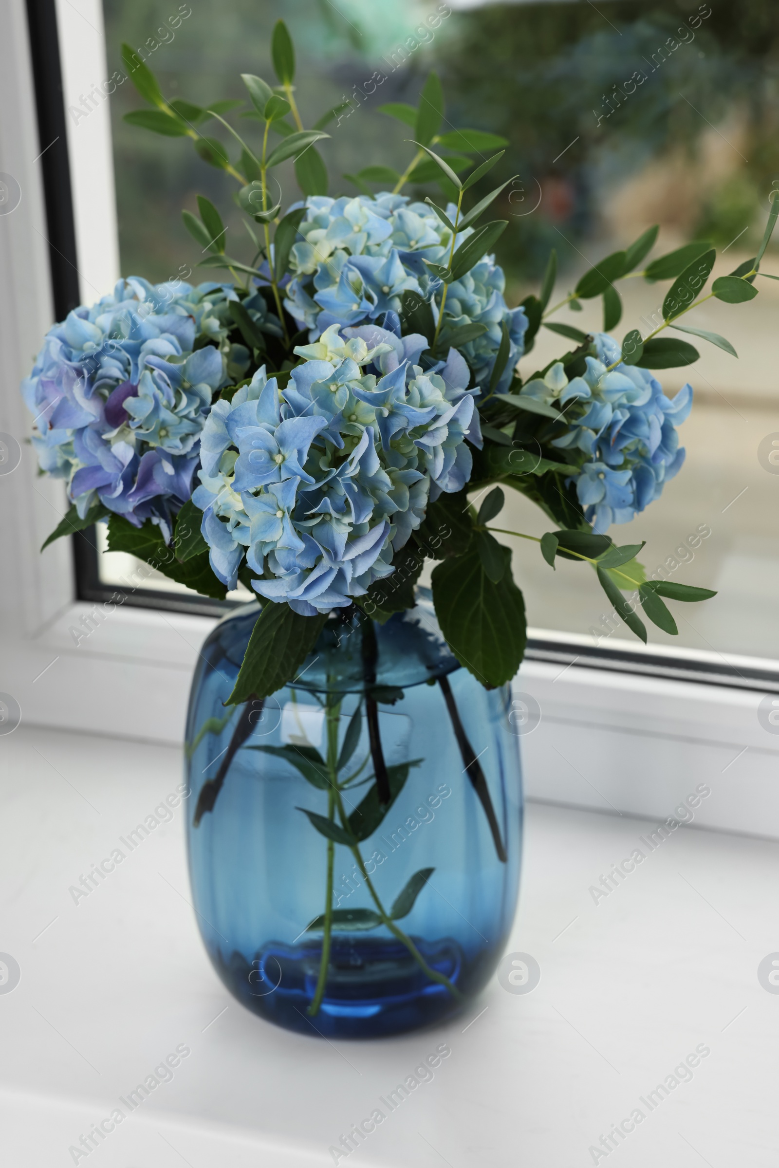 Photo of Beautiful blue hortensia flowers in vase on window sill indoors