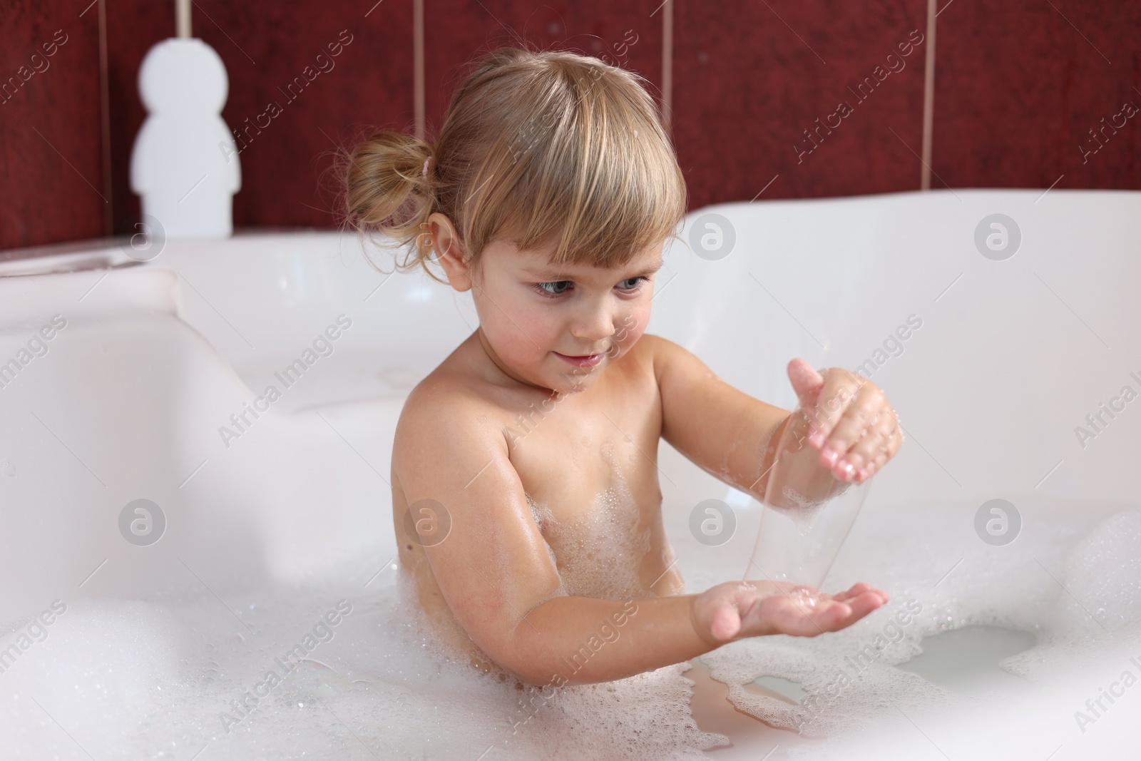 Photo of Little girl having fun in bathtub at home