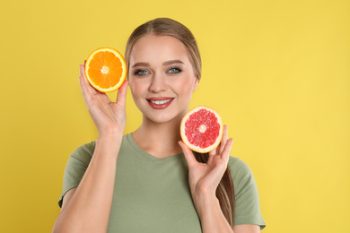 Photo of Young woman with cut orange and grapefruit on yellow background. Vitamin rich food