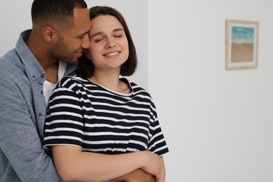 Dating agency. Couple hugging near window at home, space for text