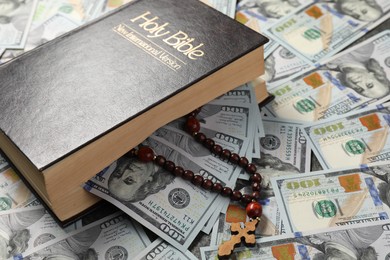 Photo of Holy Bible and wooden cross on dollar banknotes, closeup