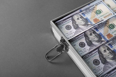 Photo of Briefcase with banknotes on grey table, closeup. Space for text