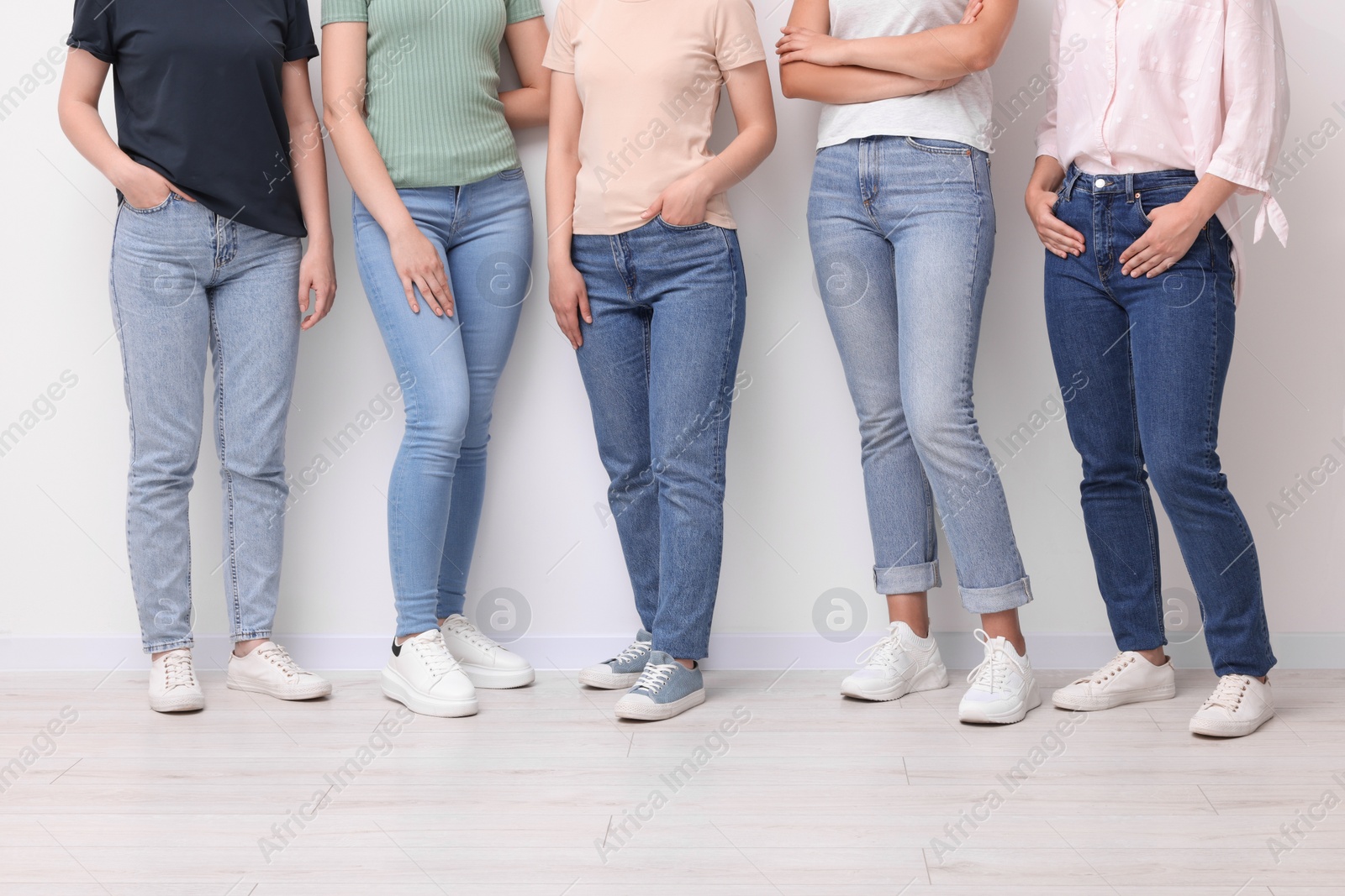 Photo of Women in stylish jeans near white wall, closeup