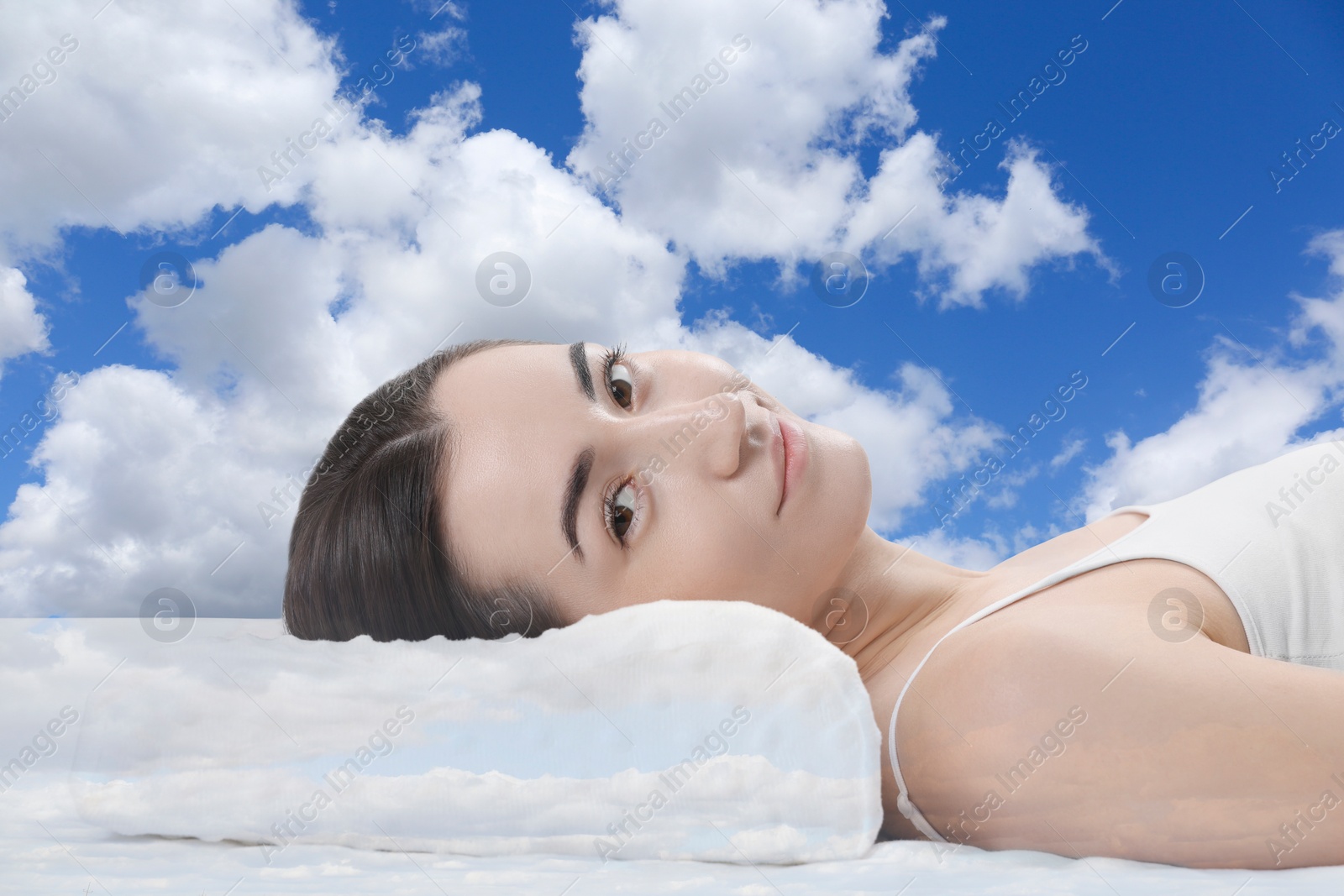Image of Woman lying on orthopedic pillow against blue sky
