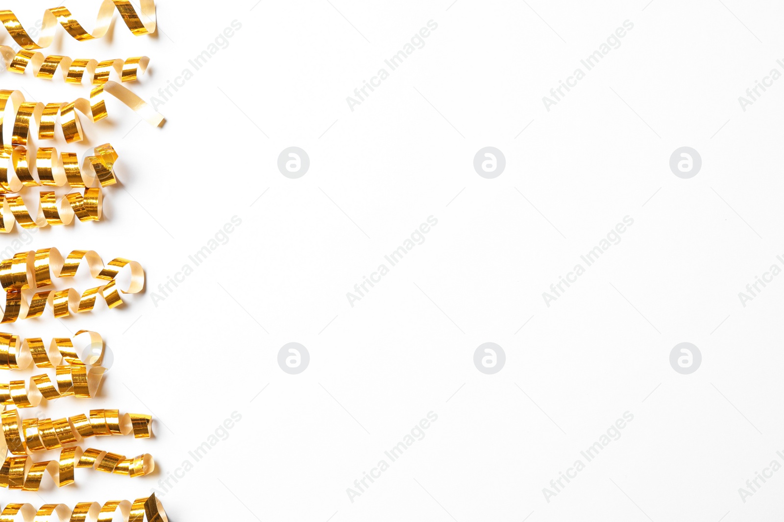 Photo of Shiny golden serpentine streamers on white background, top view