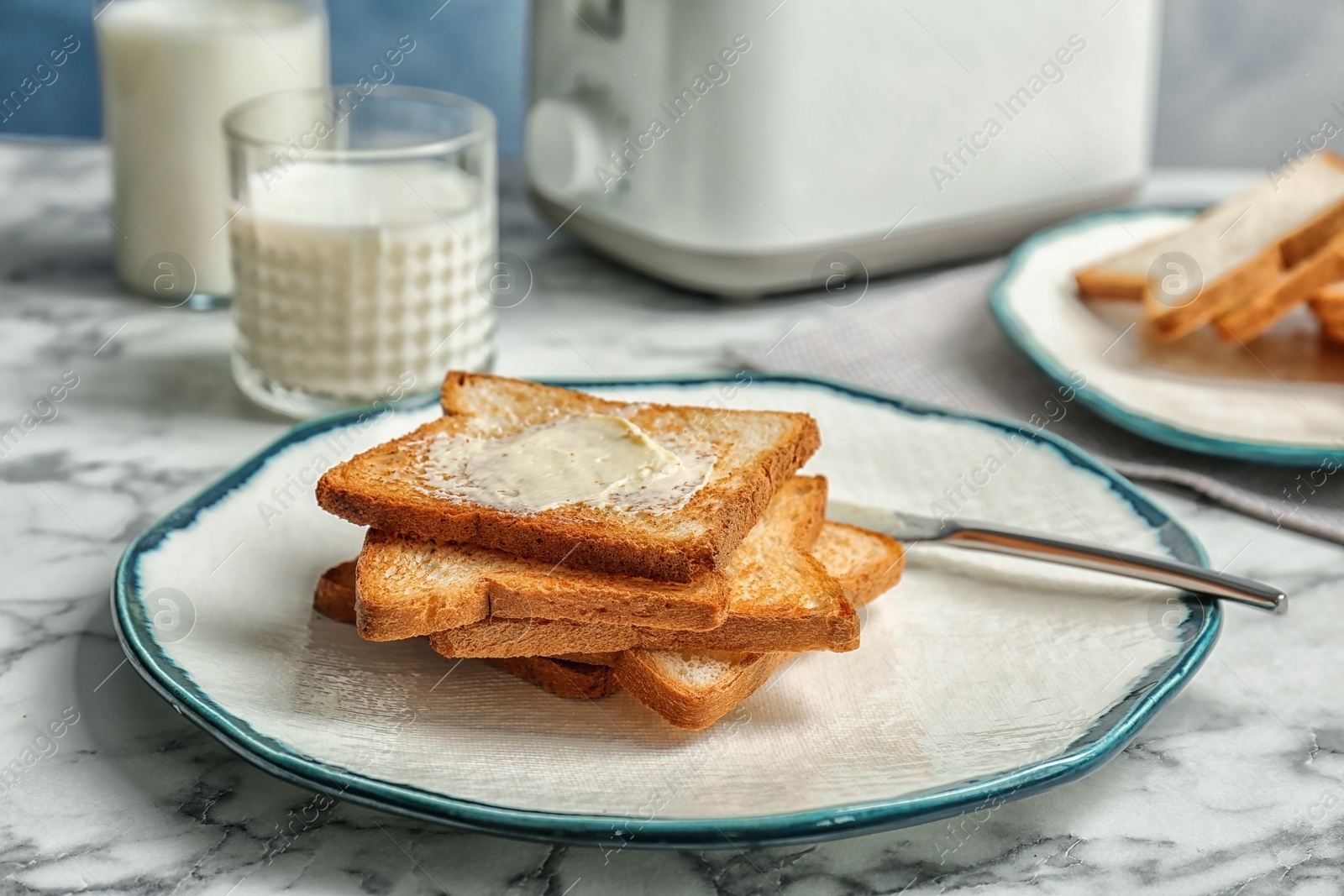 Photo of Plate with toasted bread and butter on table