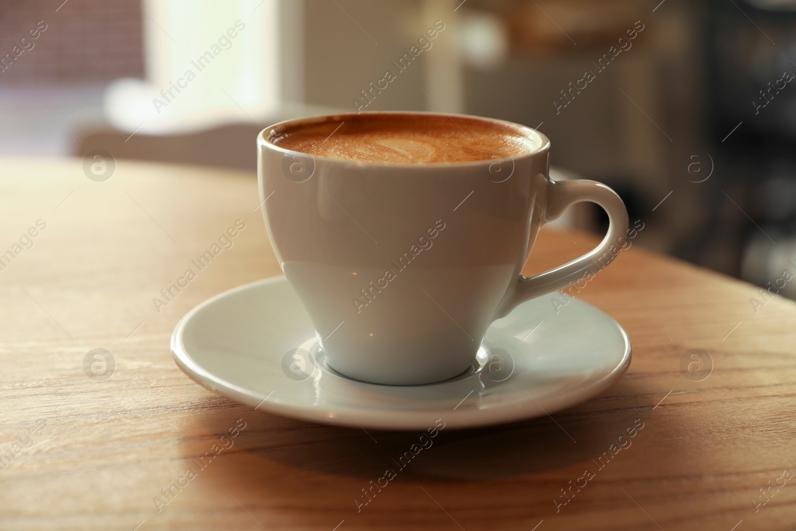 Photo of Cup of aromatic hot coffee on wooden table in cafe, closeup